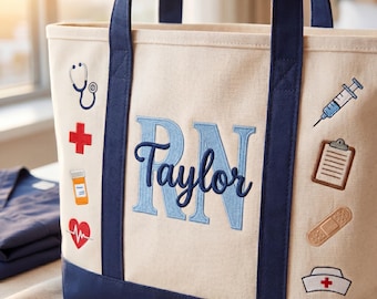 May include: Cream-colored canvas tote bag with navy blue accents. Features embroidered medical symbols and the letters "RN" in light blue, with the name "Taylor" below. Includes a stethoscope, cross, pill bottle, and heart rate symbol.