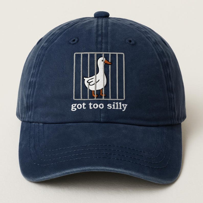 May include: A navy blue baseball cap with a white goose in a cage graphic and the text "got too silly".
