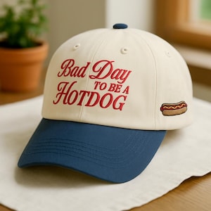 May include: A white ceramic mug with a black handle and the text "But First, Coffee" in a bold, black font. The mug is set against a blurred background, suggesting a cozy setting.