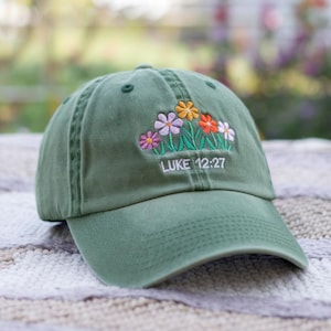 May include: A green baseball cap with embroidered flowers and the text "LUKE 12:27".