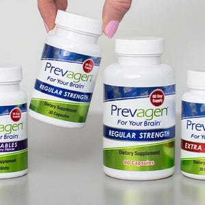 May include: Several white bottles of Prevagen dietary supplements are displayed. The bottles have blue and white labels with the brand name and product information. Some bottles are labeled "Chewables" and "Extra Strength". One bottle is being held by a hand.