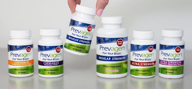 May include: Several white bottles of Prevagen dietary supplements are displayed. The bottles have blue and white labels with the brand name and product information. Some bottles are labeled "Chewables" and "Extra Strength". One bottle is being held by a hand.