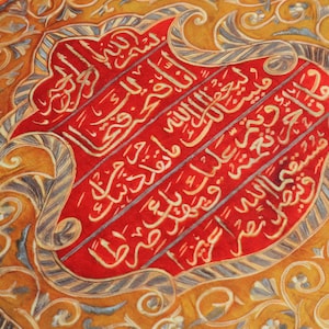 Pu&ograve; includere: Primo piano di un tessuto rosso e oro con motivi intricati e calligrafia araba. Il tessuto &egrave; decorato con filo d'oro e ha una texture in rilievo.