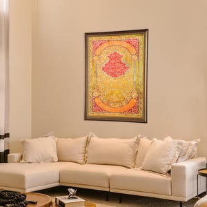 Pu&ograve; includere: Un divano componibile bianco con cuscini beige in un soggiorno con un'opera d'arte incorniciata che presenta calligrafia dorata e rossa su sfondo giallo.