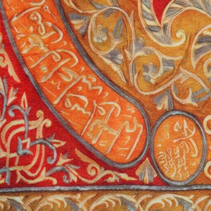 Pu&ograve; includere: Primo piano di un tessuto con un motivo floreale intricato e ripetitivo in tonalit&agrave; di arancio, rosso e blu. Il tessuto ha un aspetto testurizzato, quasi intrecciato.