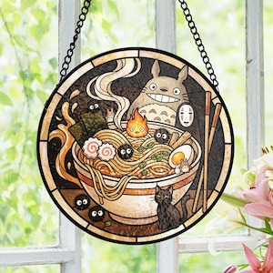 May include: Round stained glass window featuring a ramen bowl with anime characters. The bowl is filled with noodles, eggs, and other ingredients. A large, smiling character is above the bowl. A black cat sits below the bowl.