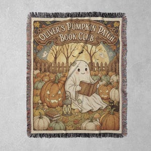 May include: A woven throw blanket featuring a ghost reading a book in a pumpkin patch with the text Oliver's Pumpkin Patch Book Club. The design includes orange pumpkins, a lantern, autumn leaves, a wooden fence, and a full moon background.