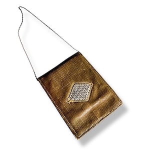 Puede incluir: Un pequeño bolso marrón con un adorno de diamante plateado. El bolso tiene una correa de cadena plateada.