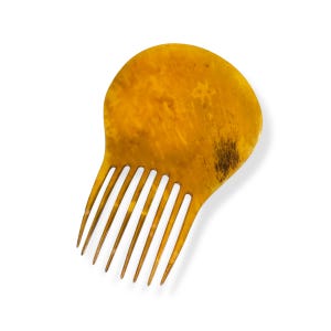 Könnte beinhalten: Ein Haarkamm im Vintage-Stil mit einem breiten, abgerundeten Griff und langen, dünnen Zinken. Der Kamm besteht aus einem warmen, bernsteinfarbenen Material mit dunkleren braunen Marmorierungen und einer glatten Oberfläche. Der Kamm ist zum Stylen und Entwirren der Haare gedacht.
