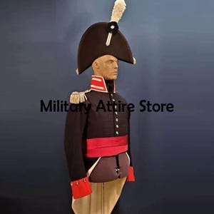 Könnte beinhalten: Eine schwarze Militäruniform mit hohem Hut und roten Akzenten. Die Uniform umfasst eine dunkle Jacke mit goldenen Schulterklappen, einen roten Schärpe und rote Manschetten. Der Text "Military Attire Store" ist sichtbar.
