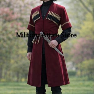 May include: A deep red chokha coat featuring black cartridge holders across the chest, short sleeves, and a black shirt underneath. A silver-toned dagger with an ornate handle is tucked into a belt at the waist. The text Military Attire Store is visible.