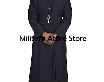 May include: A black cassock featuring a high collar with a white tab insert, long sleeves, and a matching black cincture sash with a fringed end. A silver-toned cross pendant hangs from a black cord around the neck. The text Military Attire Store is visible.