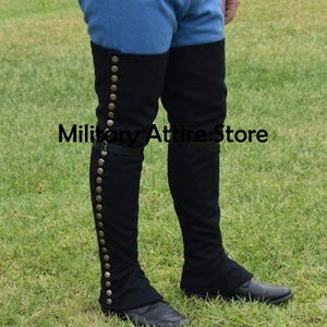 May include: Black over-the-knee gaiters featuring a vertical row of metallic buttons along the outer side and a horizontal strap across the mid-calf. The gaiters are worn over blue trousers. The text Military Attire Store is visible.