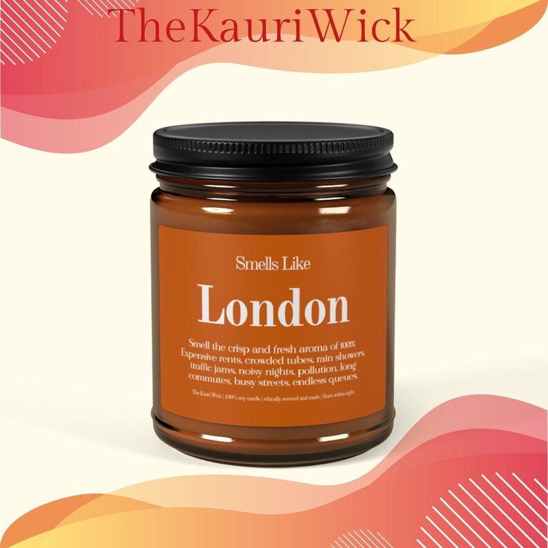 May include: A brown glass jar candle with a black lid. The label reads "Smells Like London" with text describing the scent. The Kauri Wick logo is at the top. The background has orange and pink abstract shapes.