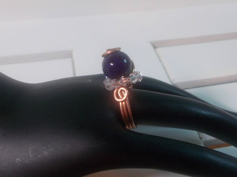 May include: A copper wire ring featuring a purple gemstone and a decorative wire design.