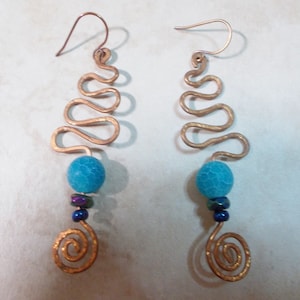 May include: A pair of gold-toned earrings with a blue agate bead and a spiral design at the bottom.