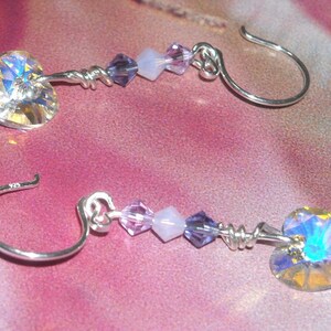 Puede incluir: Un par de pendientes de plata con un cristal en forma de corazón y cuentas moradas y blancas.