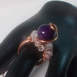 May include: A copper wire ring featuring a purple gemstone and clear crystal beads.