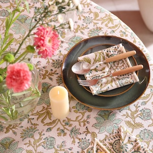 Puede incluir: Una mesa puesta con un mantel floral, un plato verde oscuro y una servilleta estampada. Cubiertos con mangos de madera descansan sobre la servilleta. Un jarr&oacute;n de cristal contiene flores rosas y una vela color crema.