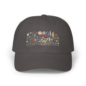 May include: A dark gray baseball cap with an embroidered design of a field of wildflowers in shades of white, orange, and yellow.