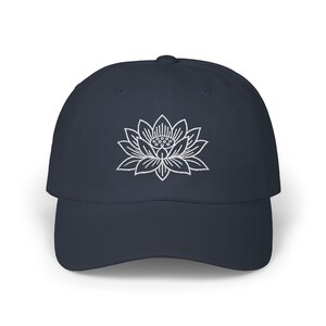 May include: A navy blue baseball cap with a white embroidered lotus flower design.