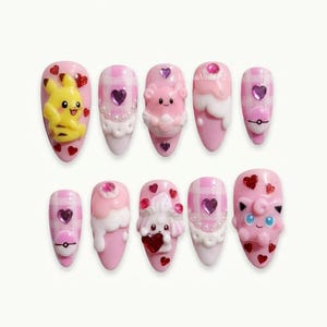 Peut inclure: Un ensemble de dix faux ongles avec des motifs à carreaux roses, des figurines 3D dont Pikachu et Rondoudou, des accents blancs crémeux, de petits ornements en forme de cœur rouge, des strass violets en forme de cœur et des Poké Balls miniatures.