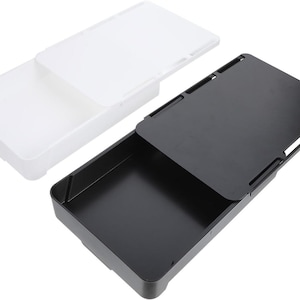 Op de afbeelding: Twee rechthoekige opbergbakken, één witte en één zwarte, met schuifdeksels. Het deksel van de witte bak is gedeeltelijk open, waardoor de binnenkant zichtbaar is. Het deksel van de zwarte bak is open. Beide bakken zijn van glad materiaal.