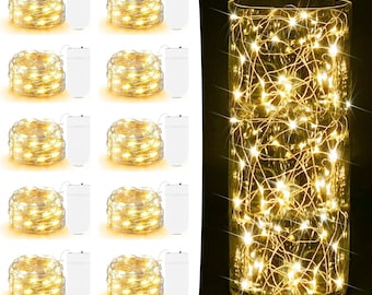 May include: A collection of warm white LED string lights, coiled and paired with white battery packs. A clear glass cylinder is filled with similar lights, creating a glowing display. The lights are ideal for decorative purposes.