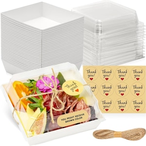May include: A stack of white square food containers with clear lids, a prepared food container with a clear lid, and a bundle of twine. The prepared food container has a variety of food items, including fruit and meat. There are also "Thank you!" stickers.