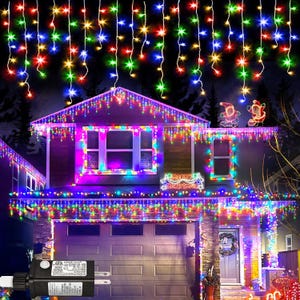 May include: A house decorated with colorful Christmas lights. The roofline and windows are outlined with strings of lights in red, green, blue, and yellow. Additional strings of lights hang down from the roof. Two Santa figures are on the roof.