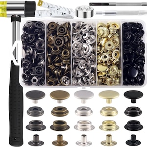 May include: A set of 100 snap fasteners in black, silver, and gold. The set includes a hammer, a tool for setting the snaps, and a measuring tape. The snaps are arranged in three rows of four, with each row containing a different color. The snaps are made of metal and have a shiny finish.
