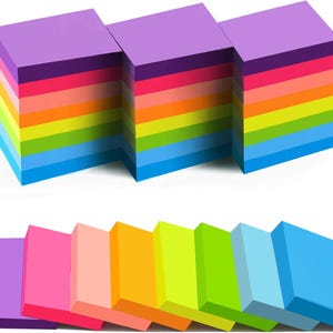 May include: A collection of rainbow-coloured sticky note pads. Each pad is made up of individual sheets in a spectrum of colours, from purple to blue. The image also shows a row of individual sticky notes in various colours.
