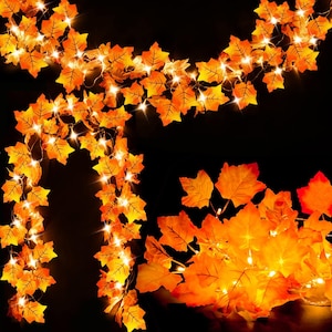 May include: A string of orange maple leaf lights with small, bright white lights. The leaves are a warm orange color, and the lights are evenly spaced along the wire. Perfect for fall or autumn decor.