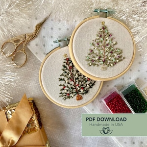 Pode incluir: Dois enfeites de árvore de Natal bordados em aros de madeira. As árvores são decoradas com contas vermelhas, verdes e douradas. Uma tesoura dourada e um presente embrulhado com uma fita dourada também estão na imagem.