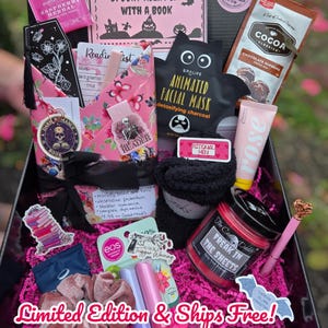 May include: A gift box filled with self-care items and reading accessories. Includes a face mask, lip mask, cocoa mix, socks, a candle, and a pen. The box is decorated with pink and black accents, stickers, and the text "Spooky Night In With A Book."