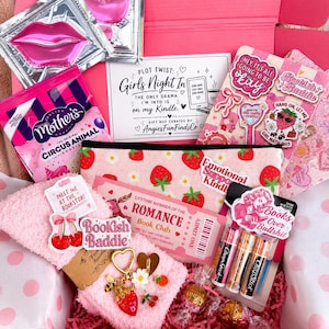 May include: A pink gift box containing a strawberry-patterned pouch, a pair of fuzzy pink socks, a gold-toned charm keychain, a pack of lip balm, Mother's Circus Animal cookies, two lip mask packets, a romance book club card, and various stickers.