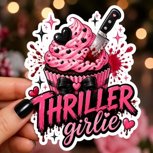 May include: A die-cut sticker featuring a chocolate cupcake with pink frosting, black heart sprinkles, and a black bow. A silver knife with a blood-stained blade is inserted into the frosting. The text reads THRILLER girlie in pink and black.