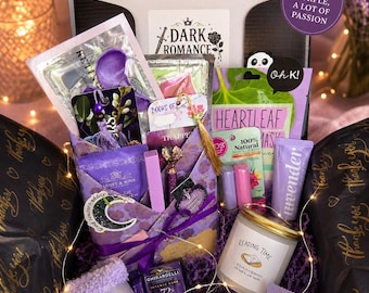 May include: A Purple Passion Box filled with self-care items. The box includes a variety of purple-themed products such as socks, a candle, lavender shower steamer, and a face mask. The box is decorated with fairy lights and the text "Purple Passion Box".