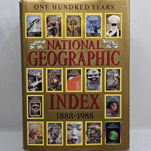 May include: A gold-colored book titled "National Geographic Index 1888-1988." The cover features the magazine's logo and multiple small images of past covers. The text "One Hundred Years" is at the top.