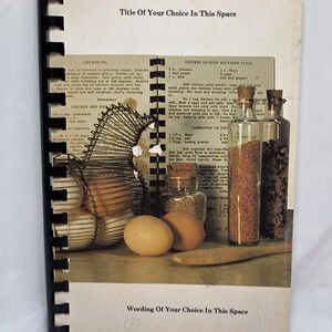 May include: A spiral-bound cookbook with a white cover featuring a vintage kitchen scene. The cover displays text reading Title Of Your Choice In This Space and Wording Of Your Choice In This Space, alongside images of eggs, spices, and a wire basket.