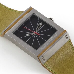 May include: A silver square watch with a black face and a green leather band. The watch face has a red second hand and a white minute hand. The watch is labeled "Francik" on the side.