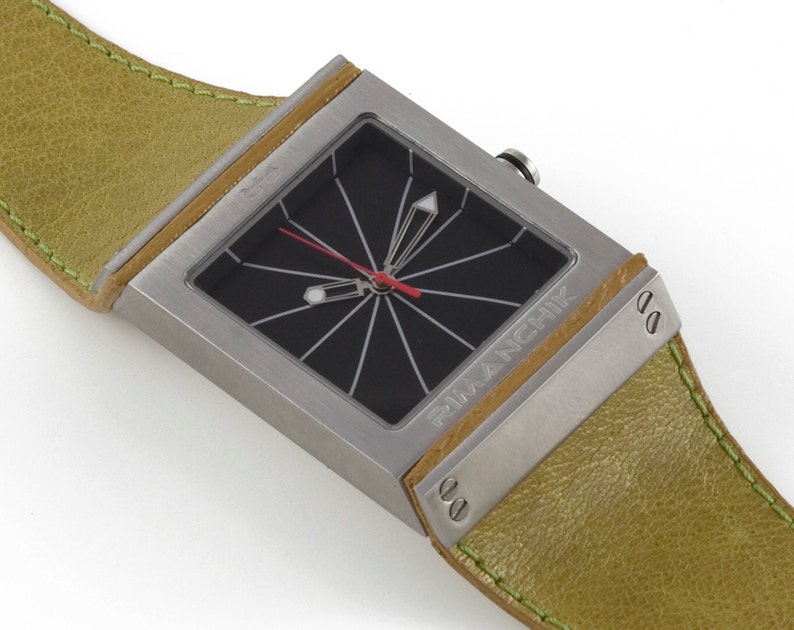 May include: A silver square watch with a black face and a green leather band. The watch face has a red second hand and a white minute hand. The watch is labeled "Francik" on the side.