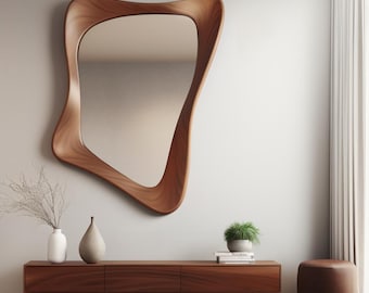 May include: A wooden console table with three drawers, a brown leather ottoman, and a large, abstract, wooden framed mirror on a white wall.  The console table has a light wood finish and the ottoman is round.