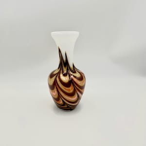 Può includere: Un vaso decorativo in vetro con la parte superiore bianca e una base bulbosa. La base presenta un motivo a spirale di tonalità marroni, dorate e rosa. Il vaso ha un collo stretto e un'apertura svasata, adatto per esporre fiori.