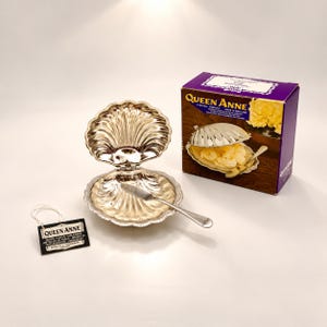 May include: A silver-plated shell-shaped dish with a hinged lid and a matching small spreader knife. The set includes a purple Queen Anne product box and a black tag with the text Queen Anne Silver Plated Tableware, Made in England.