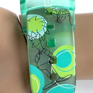 May include: A clear green watch with a cartoon character design. The watch band features a teal and green colour scheme with a cartoon character illustration. The watch is on a wrist.