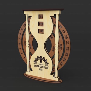May include: A wooden hourglass-shaped perpetual calendar with a rotating date wheel. The calendar displays the date, month, and day. The text "LASER CUT FILES ART" is visible on the front. The calendar is made of light and dark brown wood.