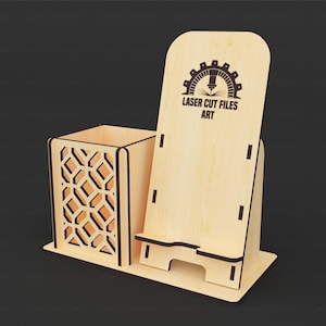 May include: A light-colored wooden desk organizer featuring a square pen holder with a geometric lattice cutout pattern and an integrated upright mobile phone stand. The phone stand displays the black text LASER CUT FILES ART with a gear icon.