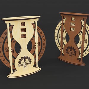 May include: Two wooden hourglass-shaped calendars with a gear design and the text "LASER CUT FILES ART." One is light wood, the other is dark wood. Each calendar displays the date, month, and day. The calendars are set against a dark background.