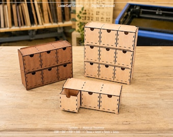 May include: Three wooden storage organizers with drawers, featuring a modular design with visible laser-cut joints. One unit is dark brown, while two are light tan. Each drawer has a circular cutout handle. Text includes LaserCutFilesArts.